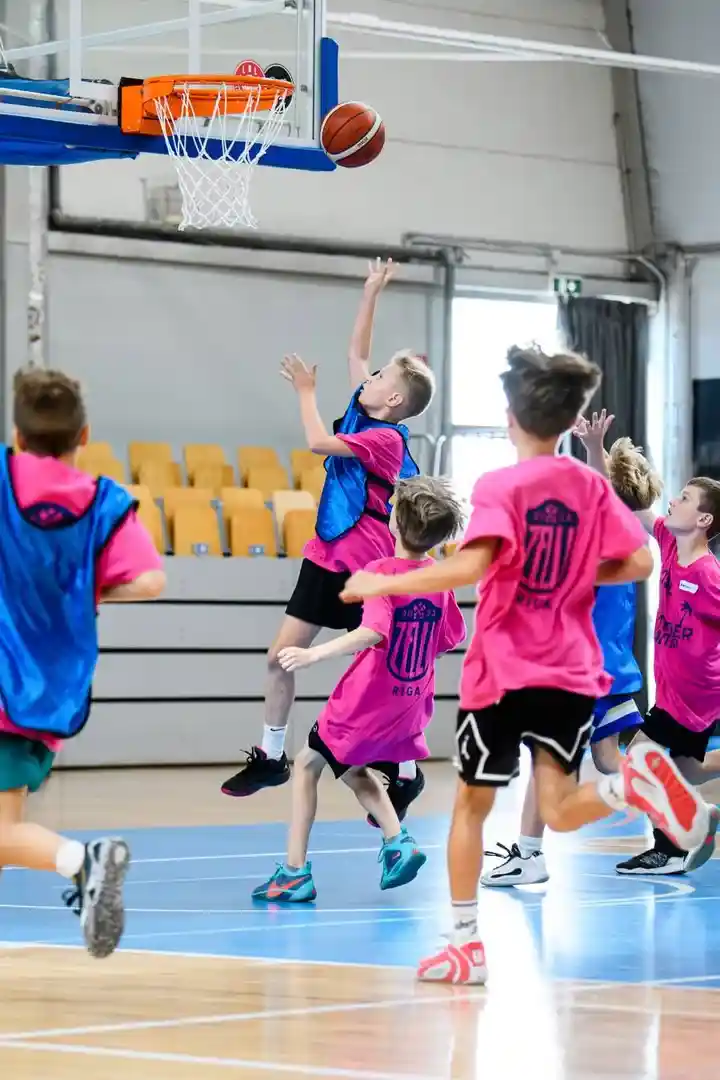 Bērni spēlē basketbolu sporta zālē
